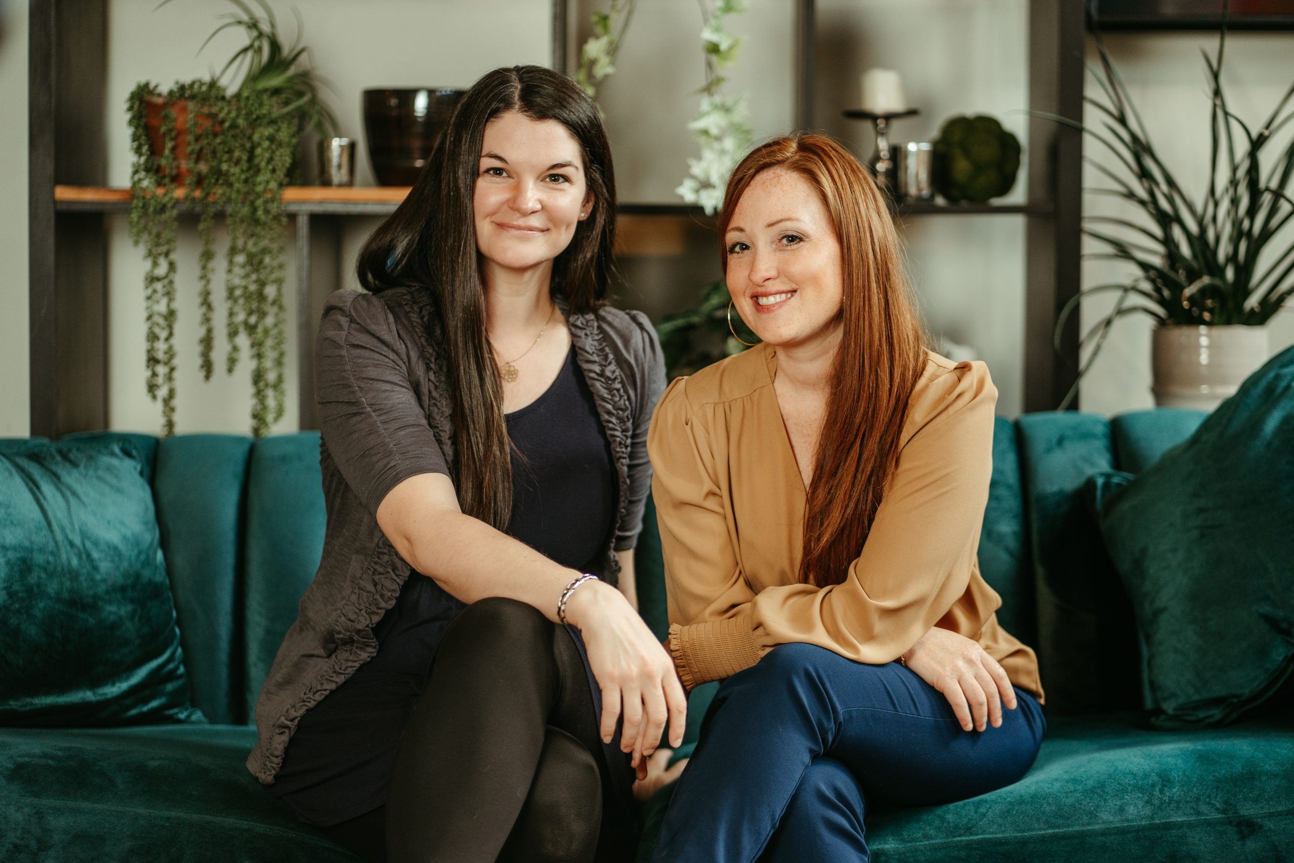 nimblweb-15 Two women sitting on a green velvet couch smiling at the camera